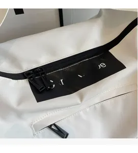 Detail of white canvas gym bag showing black logo patch and durable matte metal zipper