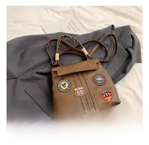 Detail of vintage brown leather handbag with embroidered badges and woven top handle