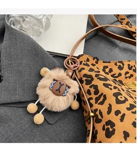 Dettaglio del ciondolo a capibara in peluche con borsa leopardata e campanellino in metallo