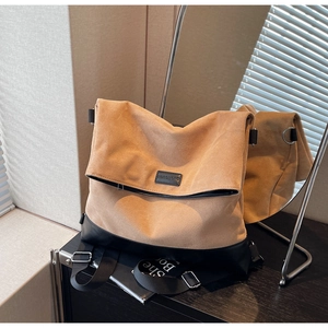 Detailed close-up of brown suede messenger bag with black leather base and adjustable strap