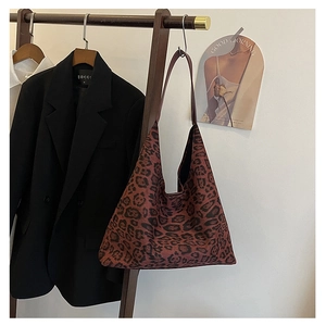Detail of a large leopard print tote bag styled with a blazer on a wooden hanger