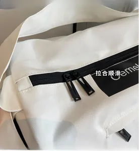 Close-up of smooth black double zippers and Gemel logo on white fabric travel bag