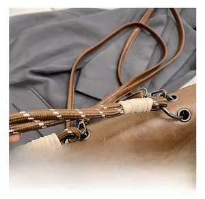 Close-up of vintage brown leather bag with braided rope handles and matte metal rings