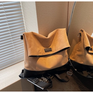 Detail of khaki suede tote bag showing large foldable top and black leather base