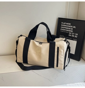 Dettaglio borsa da viaggio crema con cinghie nere e tasche con zip su marmo