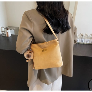 Detail of a vintage mustard suede shoulder bag with a teddy bear charm and gold lock
