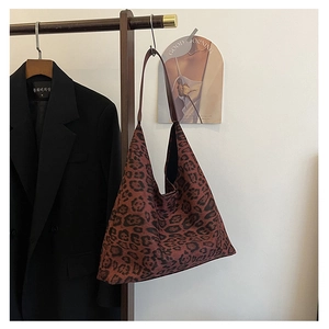 Detailed view of leopard print tote bag hanging on a wooden rack with dark blazer