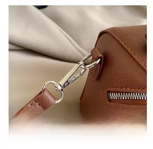Détails des crochets métalliques et du zip sur un sac polochon marron vintage