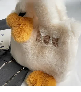 Détail d'un sac peluche canard blanc avec broderie JOY et bandoulière en chaîne dorée