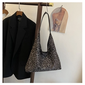Detail of a large leopard print tote bag with soft texture hanging on a wooden hanger