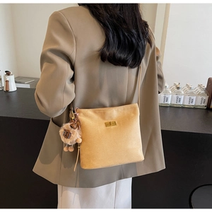 Detail view of khaki suede bucket bag with gold clasp and plush lion pendant charm
