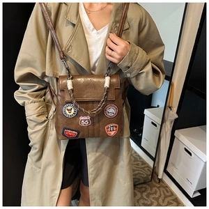 Close-up of vintage brown leather backpack with retro embroidery patches and rope handle detail