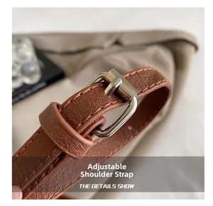 Gros plan sur la bandoulière réglable en cuir marron avec boucle en métal argenté