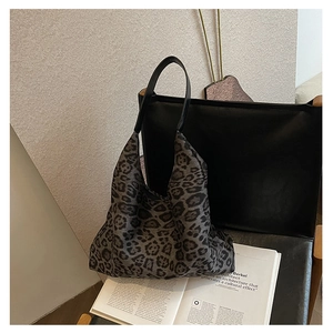 Detailed close-up of leopard print fabric tote bag with black leather straps on a chair