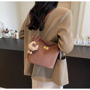 Close-up of vintage brown suede bucket bag with gold clasp and plush bear charm