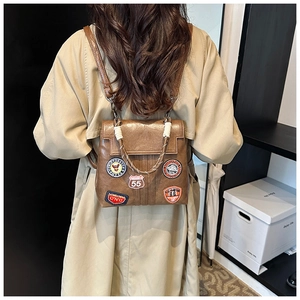 Detail of vintage brown leather backpack with retro patches and woven rope handle