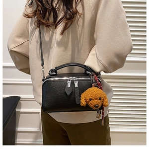 Détail d'un sac Boston en cuir noir avec un joli pendentif en forme d'ours en peluche