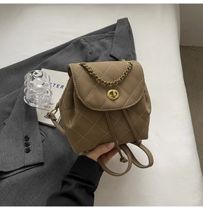 Detail van beige gewatteerde rugzak met gouden draaisluiting en elegante kettinggreep