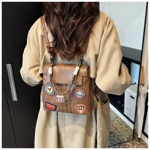 Detail of vintage brown leather backpack with retro embroidery patches and woven handle