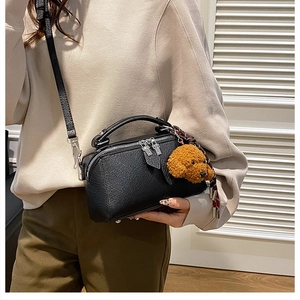 Détail du sac oreiller en cuir noir avec charm chien en peluche et foulard en soie