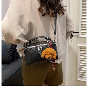 Vue détaillée du mini sac polochon noir grainé avec breloque peluche de chiot
