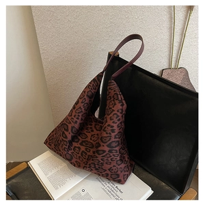 Detailed view of red leopard print tote bag with leather straps on a vintage chair