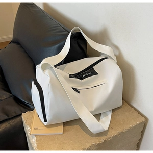 Close-up of white cylindrical sports bag with black zipper and wide nylon shoulder strap
