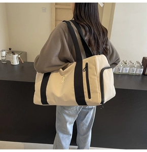 Dettaglio borsa fitness crema con cinghie nere e scomparto laterale per oggetti