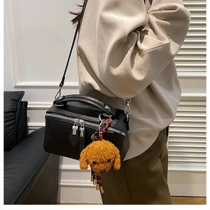 Détail d'un sac oreiller en cuir grainé noir avec un charmant caniche en peluche