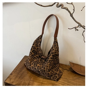 Close-up of leopard print tote bag with brown leather strap on a rustic wooden surface