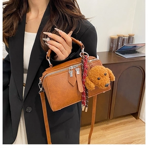 Détail d'un sac à main vintage en cuir marron avec un joli pendentif ours en peluche