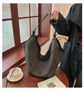 Macro detail of large leopard print tote bag with black handles on a wooden table
