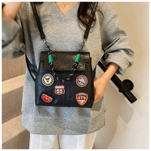 Detail of vintage black PU leather backpack showing retro embroidered patches and rope handle