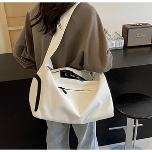 Detail view of a large white waterproof nylon travel bag worn by a model in a retro setting