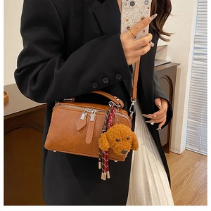 Sac polochon marron rétro avec charme peluche, porté par un mannequin en intérieur