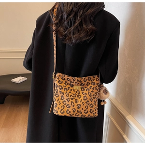 Detailed view of leopard print crossbody bag with gold twist lock and plush charm