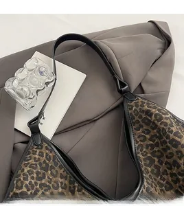 Close-up of leopard print tote bag with black shoulder strap over a gray blazer