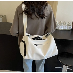 Detailed view of a white waterproof nylon travel bag with black zipper and branded shoulder strap