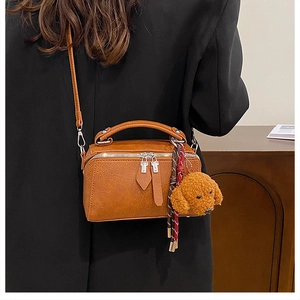 Sac oreiller vintage marron avec foulard en soie et breloque ours sur l'épaule