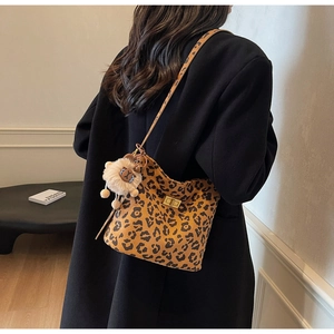 Close-up of leopard print shoulder bag with metallic twist lock and lion plush charm