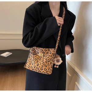 Close-up of leopard print shoulder bag with gold twist lock and furry bag charm
