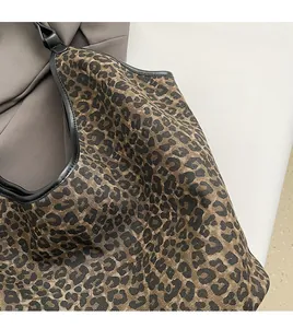Detail of leopard print canvas texture with black leather trim and durable stitching