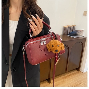 Vue détaillée du sac oreiller bordeaux avec texture litchi et breloque peluche