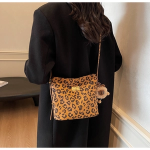 Detail of leopard print bucket bag with gold clasp and plush bear charm on a model