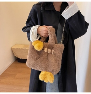 Détail d'un sac cabas en peluche marron en forme de canard avec des pattes jaunes et chaîne