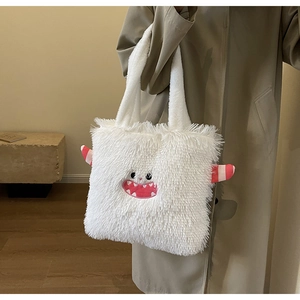 Détail du sac cabas monstre en peluche blanche avec cornes rayées et visage brodé