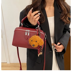 Détail du sac oreiller bordeaux avec texture litchi et pendentif ours en peluche