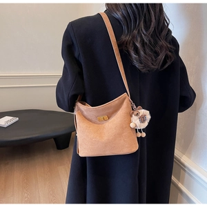 Detail of vintage brown suede bucket bag with gold clasp and sheep plush charm