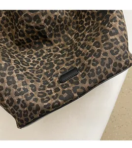 Detailed close-up of leopard print fabric tote bag with premium black leather piping edges