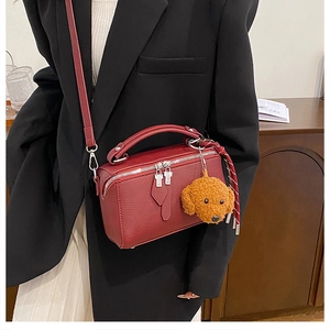 Détail du sac boîte bordeaux avec ferrures argentées et pendentif ourson en peluche